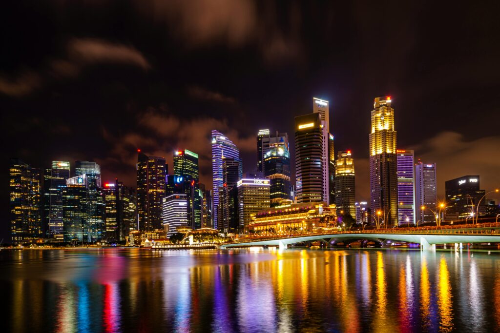 Singapore Tour Package Vibrant night view of Singapore skyline with city lights reflecting on water.